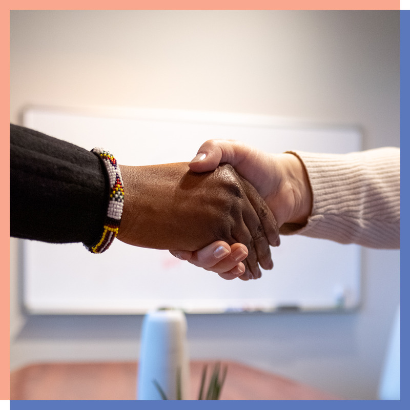 Two women shaking hands across a conference table