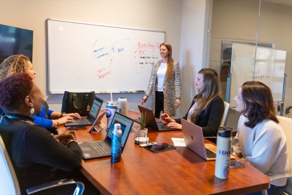 The She’s Independent team around a conference table planning Pitch Day, with mission, community and risk mapped on the whiteboard